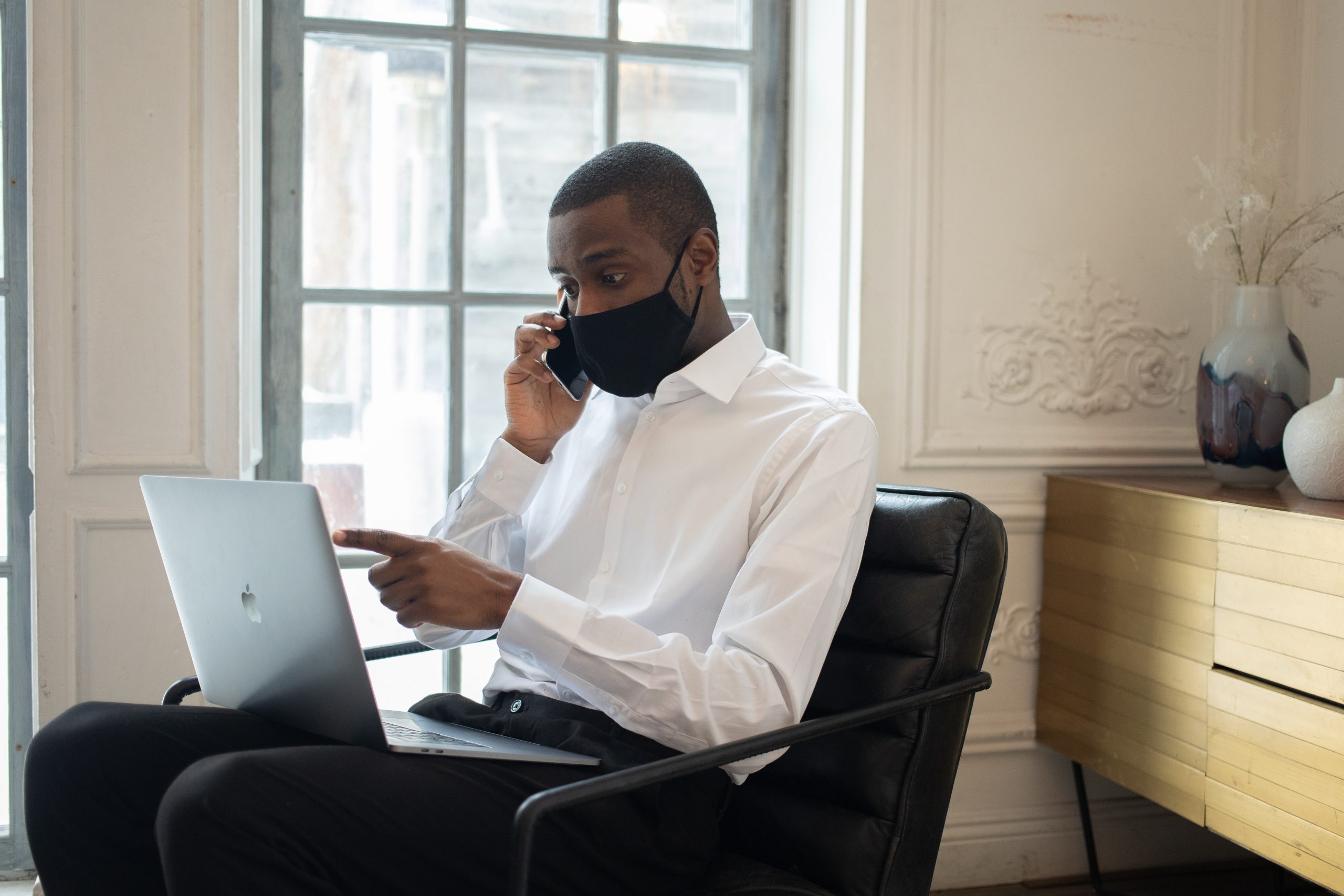 Black man wearing mask talking on phone during economic recovery discussion