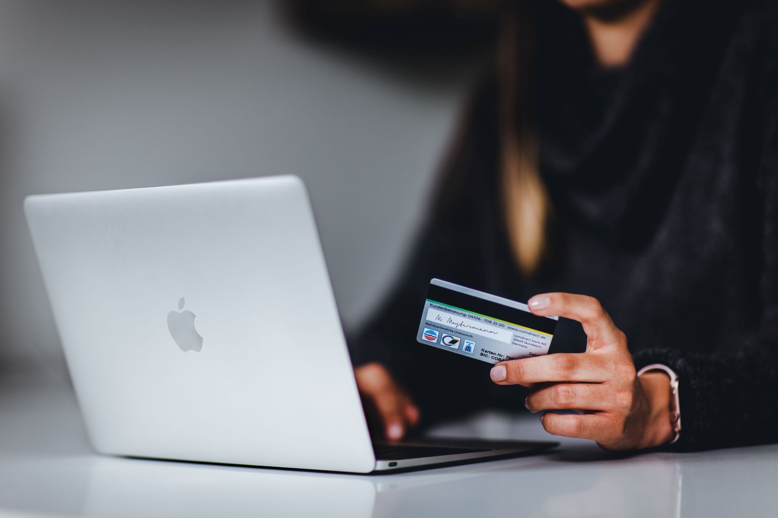 woman of color using Macbook computer and credit card to order products
